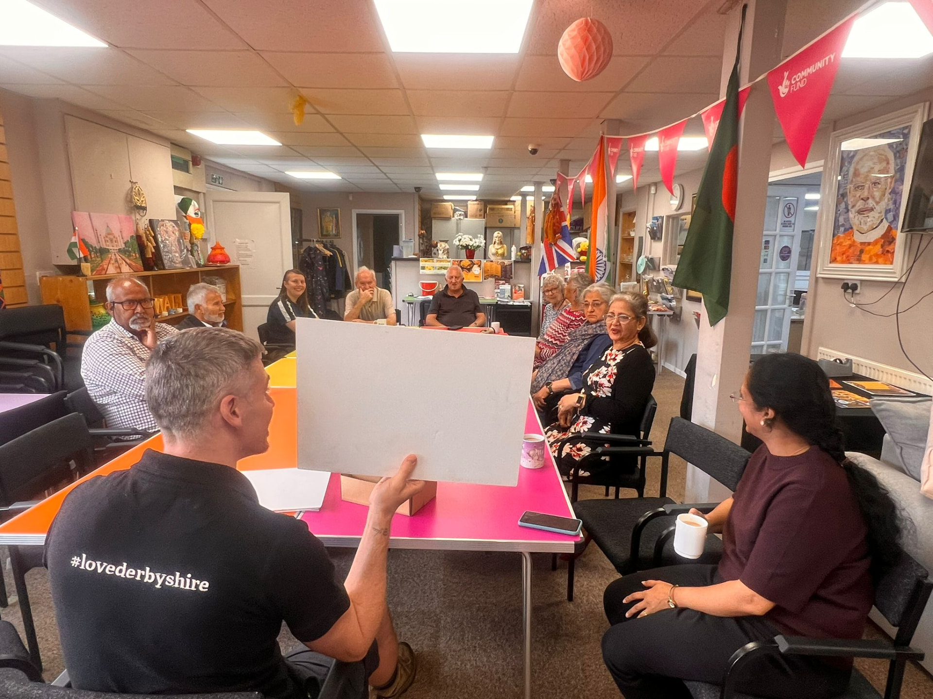 A facilitator holding up a display board to members of the Asian Association Chesterfield seated around the room