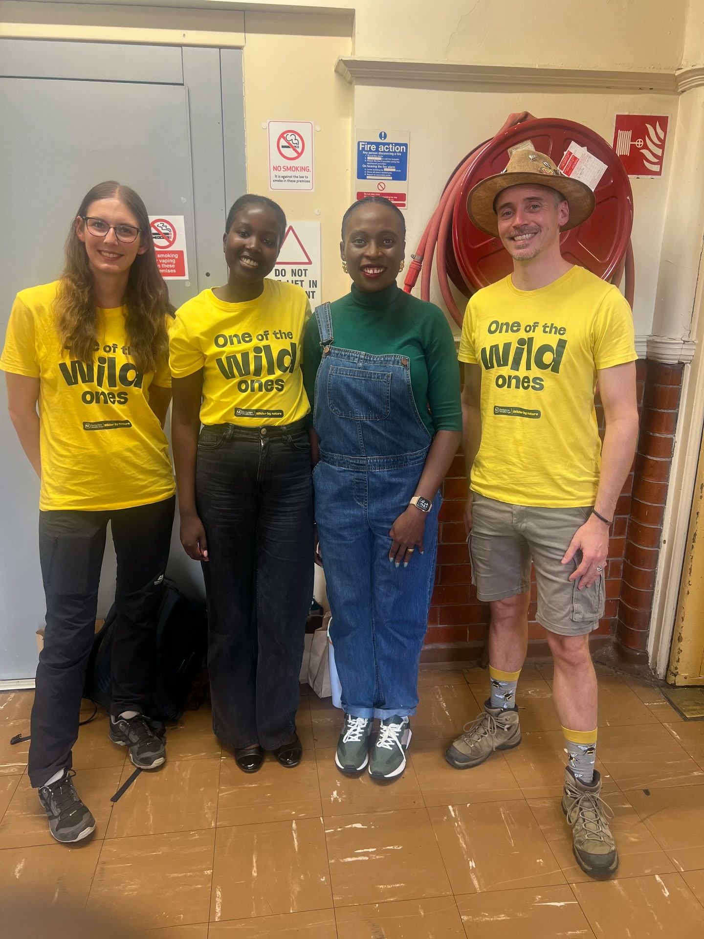 Four session facilitators wearing One of the wild ones t-shirts posing together in the venue corridor